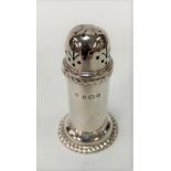 An Edwardian silver pepper caster of cylindrical form with gadrooned rim and spread foot, maker