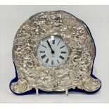 A modern silver mounted quartz timepiece embossed with cherubs and fruiting vine, maker KFLD, London