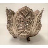 An Indian white metal lotus flower embossed bowl decorated with village scenes and flowers, raised