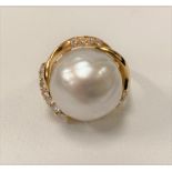 An 18ct hallmarked gold diamond and pearl set dress ring, the large central pearl surrounded by
