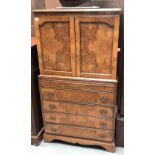 A small 20th century burr walnut veneered linen style chest, the top section with a pair of cupboard
