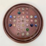 A turned mahogany solitaire board with thirty one marbles, diameter of board 35cm.