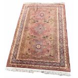 Eastern hand knotted wool rug with three medallions within multiple borders upon a madder ground,