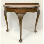 A reproduction walnut veneered demi-lune side table with foliate carved and moulded top over a