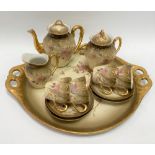 A Limoges porcelain teaset for four with ivory blush ground and gilded foliate decoration.