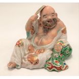 A Chinese porcelain bisque painted and famille verte glazed reclining jovial Buddha with hand fan,