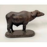 An Indian carved wood model of a water buffalo upon oval stand, width 24cm.