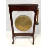 An early 20th century brass dinner gong upon mahogany frame raised on four outswept feet, height