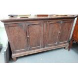 An elm low cupboard with four panelled hinged doors raised on turned feet, width 134cm
