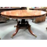A regency mahogany circular tilt-top table, the top with radiating flame veneers over the frieze