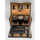 An early 20th century leather cased travelling toilet set, width 24cm.