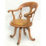 An Edwardian beech office swivel elbow chair, with later rexine upholstered seat and on four