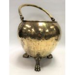 A Victorian brass ovoid coal bin with swing handle with scallop shell terminals raised on three claw