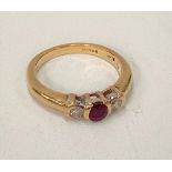 A modern 18ct hallmarked gold, diamond and ruby three stone ring, the central ruby of 0.25ct
