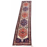 Eastern hand knotted wool runner with a row of five lozenges within borders upon a cream ground,