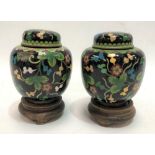 A pair of Chinese cloisonné ovoid ginger jars and covers, foliate scroll decorated upon a black