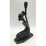 An Art Deco figural table lamp base in ebonised wood, depicting a kneeling African lady with