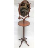 A George III style mahogany dressing stand with oval swing mirror upon shaped supports over a