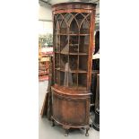 A 19th century style mahogany veneered bow front floor standing corner cabinet, raised on three