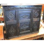 A reproduction oak low cupboard, the six panel front carved with flowerhead lozenges under an