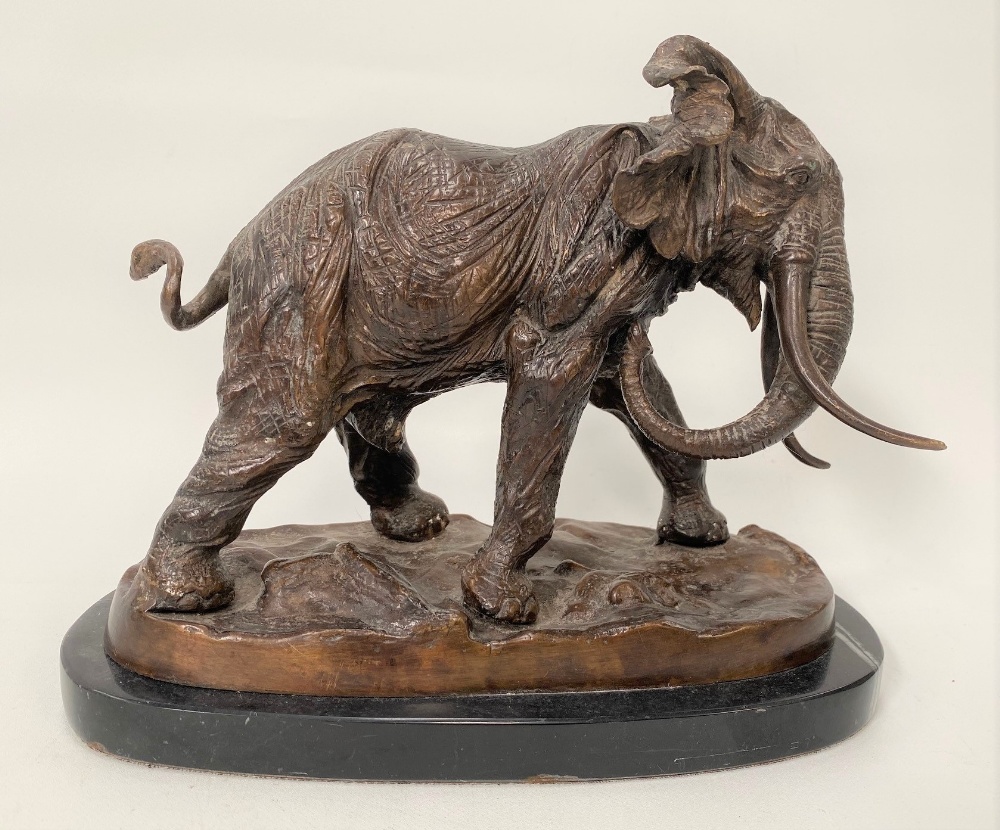 A modern bronze sculpture of a bull elephant upon a naturalistic oval base and with black marble