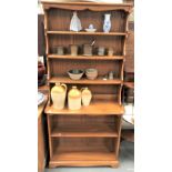 Pale elm Ercol two section dresser, the raised top with three fixed shelves, the base with an