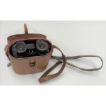 A pair of Goerz Berlin Trieder binoculars in brown leather case, the case lid inset with a compass.