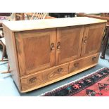 An Ercol blonde elm sideboard with three cupboards over two long drawers and on casters, width