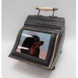 A black painted tin coal scuttle with pottery and brass handle, the hinged door with glazed panel