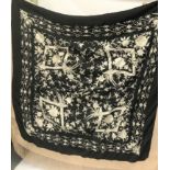 A Chinese silk embroidered shawl, in ivory stitch and knotted border upon a black ground,