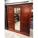 Victorian walnut triple robe, the moulded cornice over a central bevel edge mirrored door flanked by