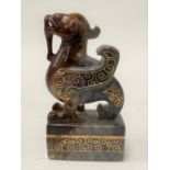 A Chinese russet and grey jade desk seal carved with gold inlay, carved as a Buddhistic lion,