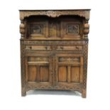A replica oak small court style cupboard, the top with two carved panelled doors flanked by turned