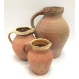 Three 19th century terracotta jugs, the largest height 32cm.