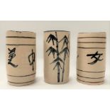A set of three Japanese pottery brush pots, two with calligraphy inscriptions, the other decorated