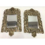 A pair of brass framed bevel edged wall mirrors, the foliate scroll moulded and pierced frame with a
