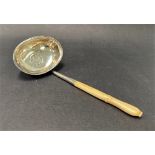 A Georgian white metal toddy ladle, with short carved ivory handle, the oval bowl set with a