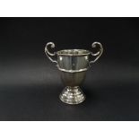 A silver hallmarked pedestal trophy cup with flying scroll handles, engraved dedication, height 12cm