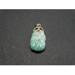 A 14ct. gold mounted jade pendant carved with a crouching monkey amongst foliage and with