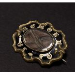 A Victorian gold plated and black enamel mourning brooch with glazed hair panel, width 38mm approx.