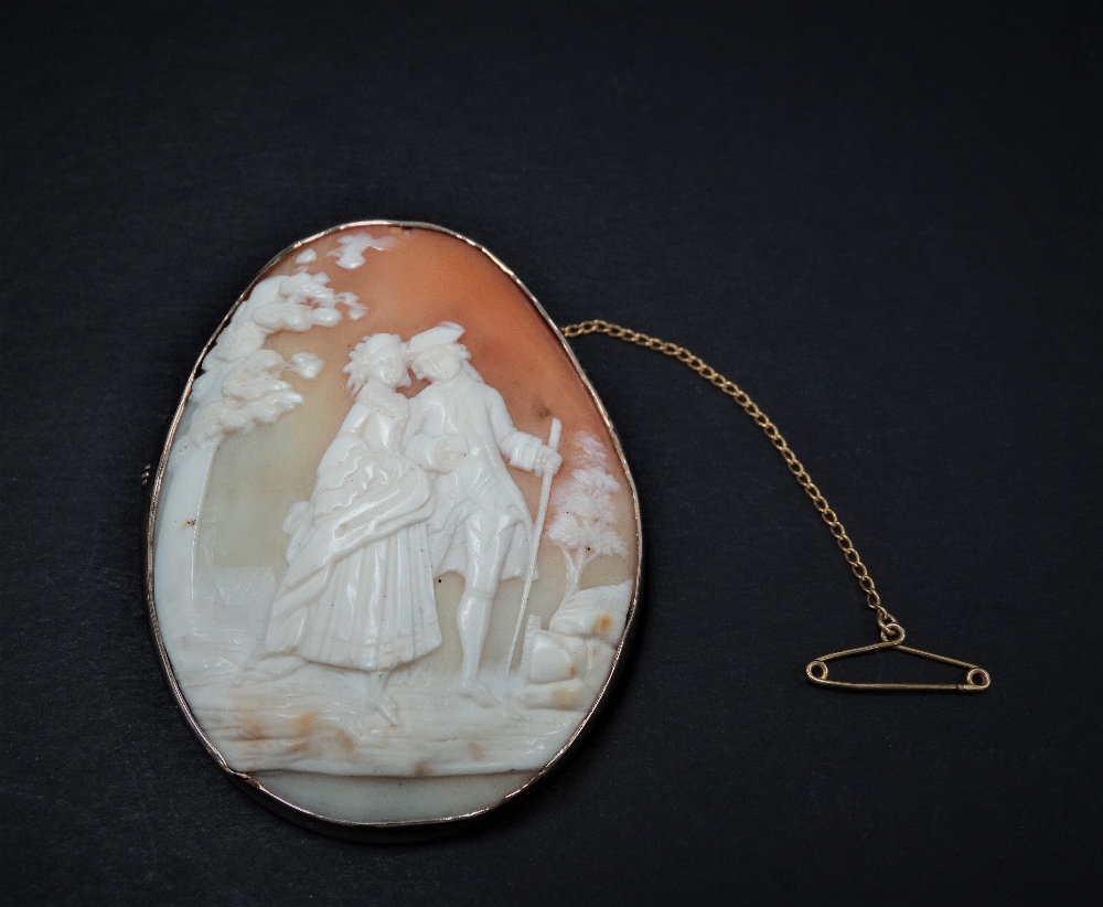 A 9ct. gold mounted oval shell cameo carved with a pair of lovers in a garden, stamped 9ct, 59 x
