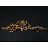 A modern 9ct. hallmarked gold Victorian style garnet set foliate scroll brooch, width 32mm,