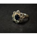 An attractive 18ct. gold sapphire and diamond nine stone cluster ring, the central oval cut sapphire