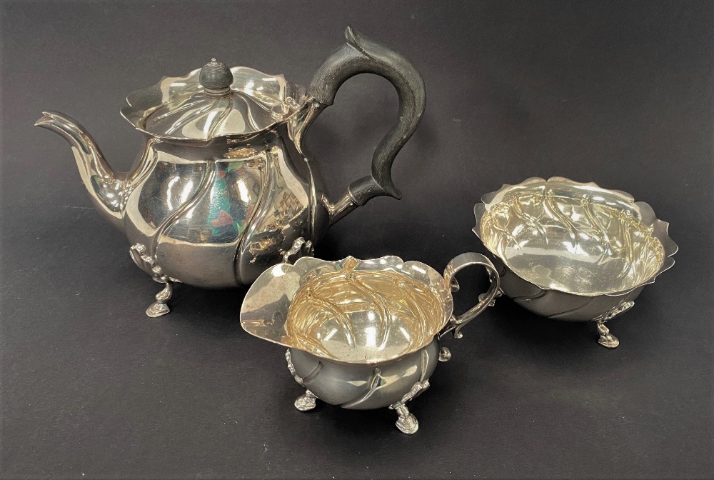 A George V silver three piece batchelor tea set, of ovoid wrythen fluted design, raised on triple