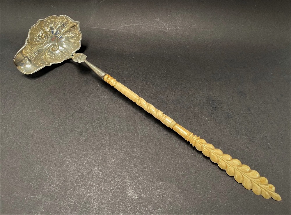 A Georgian silver ladle with ivory carved and fluted handle, with boat shaped embossed and lobed