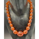 An amber faceted oval bead necklace with gold clasp, the central bead width 30mm approx., weight 69g