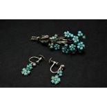 A white metal turquoise and seed pearl set floral brooch with a pair of matching screw earrings, the