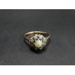 A 9ct. gold opal set nine stone cluster ring, the central cabochon opal of 0.33ct. spread approx.,