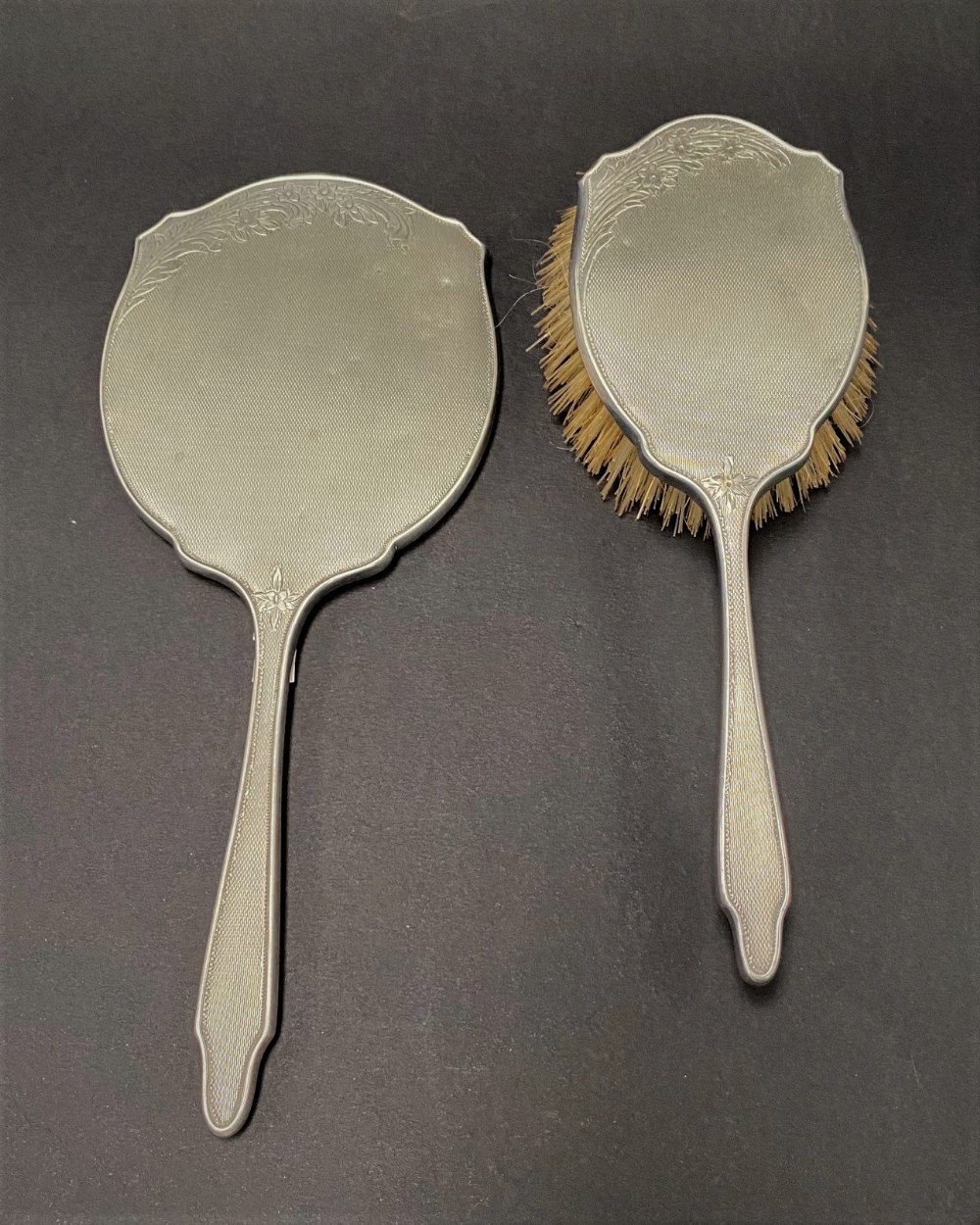 A modern engine turned silver hair brush and dressing table mirror with foliate engraved design by