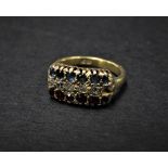 An 18ct. gold diamond ruby and sapphire set seventeen stone ring, the head set with three rows of